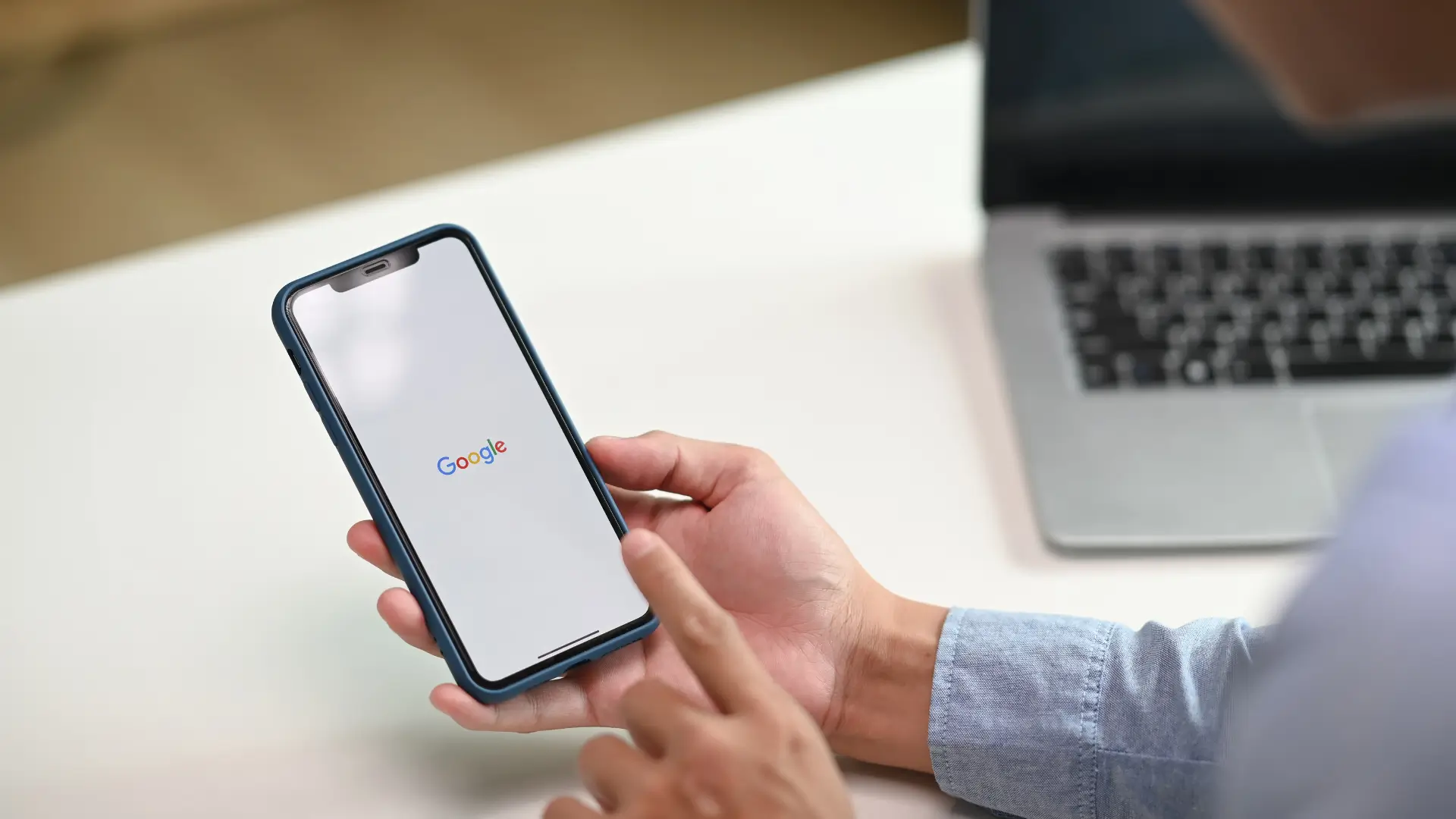 A man holding a mobile phone with the Google screen on it